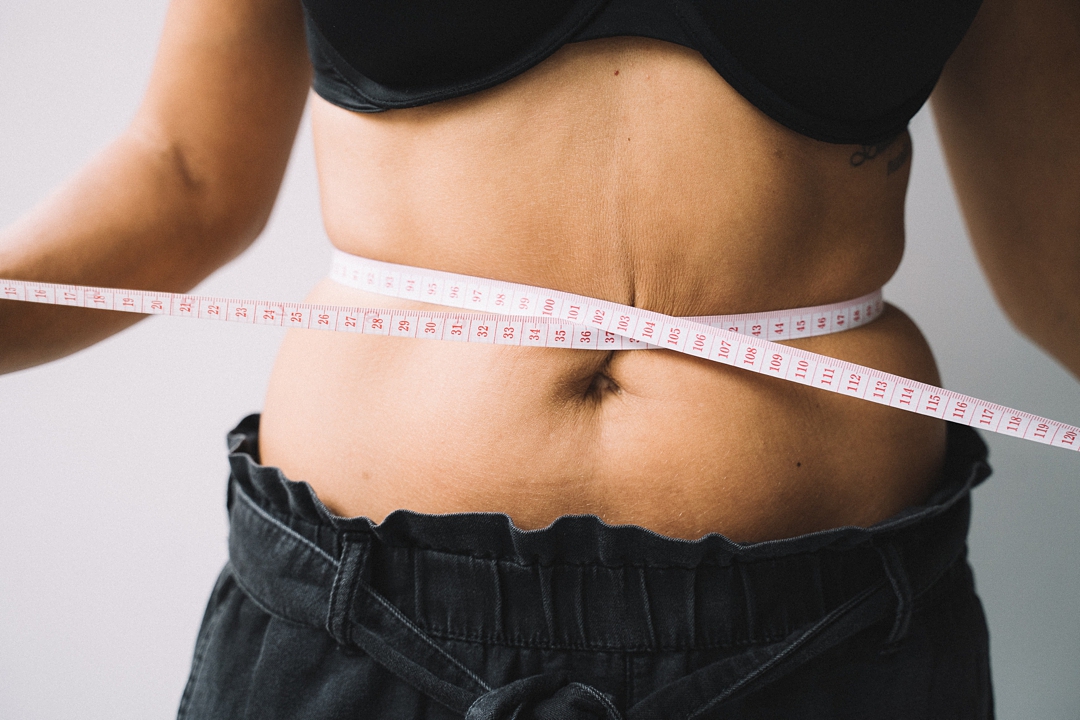 Woman measuring waist - How to not let body image hold you back by Tami Keehn.