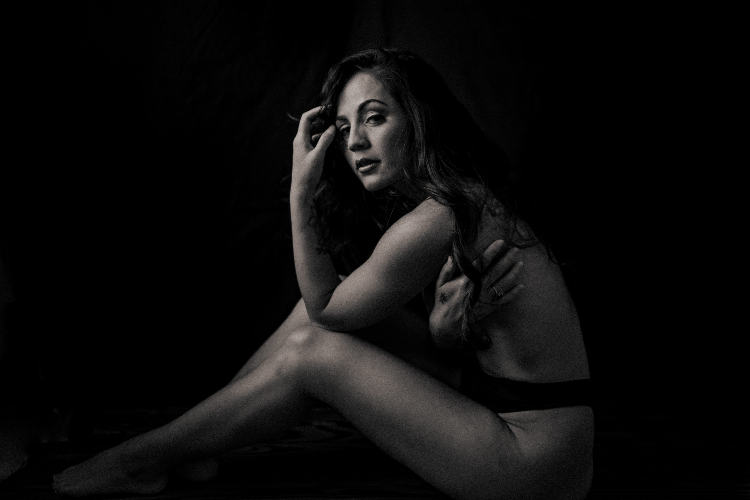 Black and White of a woman sitting topless in deep thought for a boudoir session with St Pete boudoir photographer Tami Keehn.